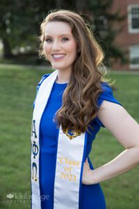 Girl with long brunette hair in royal blue dress with graduation lapel