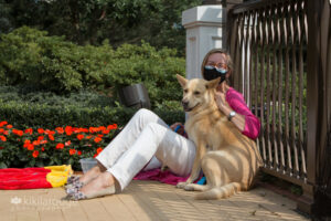 Yellow husky mix rescue dog snuggling with foster mom at adoption event at Encore
