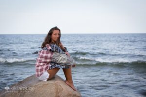 Girl sitting on rock at beach in plaid shirt