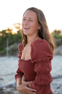 Girl laughing in dress at beach sunset