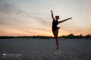 Ballet dancer jumping in silhouette with fiery sunset