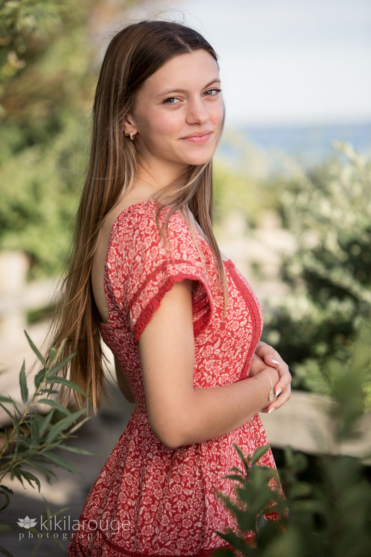 Girl with wind blown hair in red dress on beach boardwalk