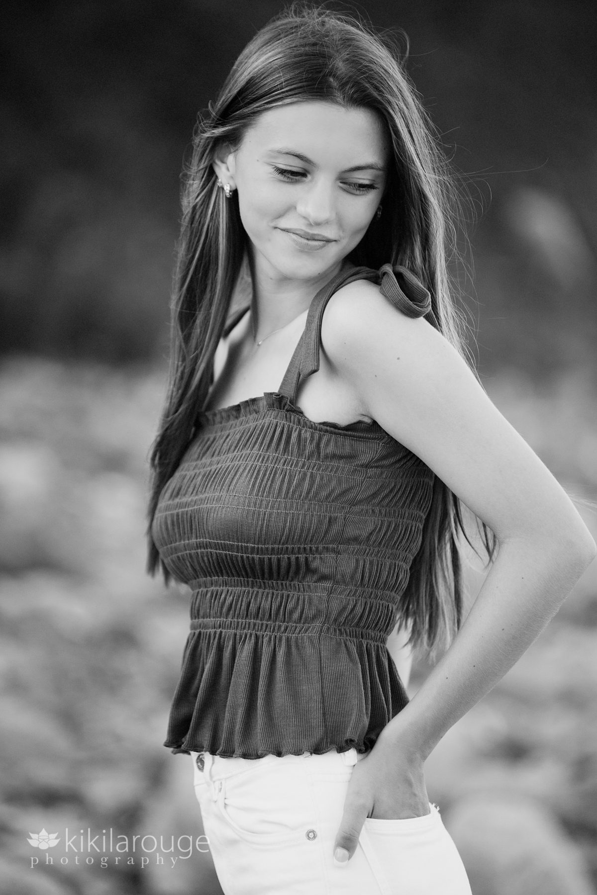 B&W portrait of teen girl in white jeans looking down smiling