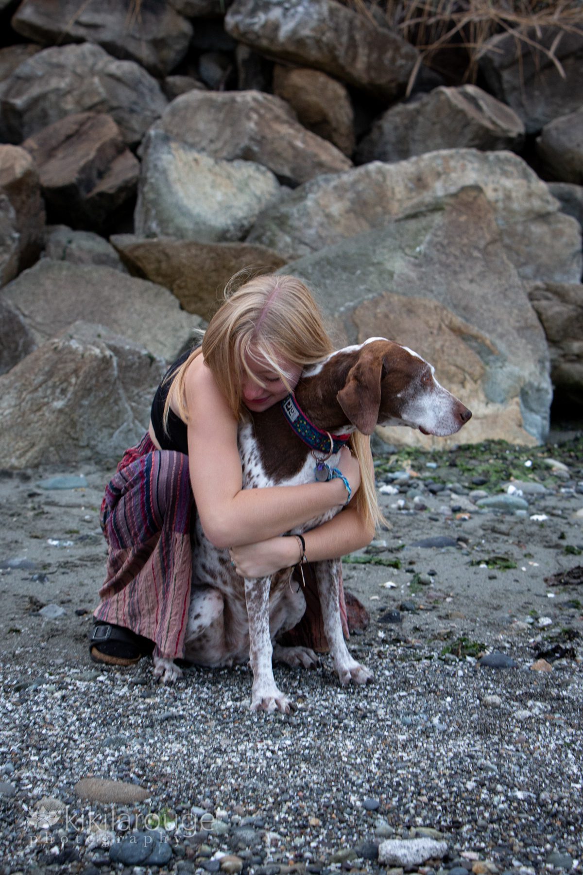 Blonde girl hugging her GSP dog at beach