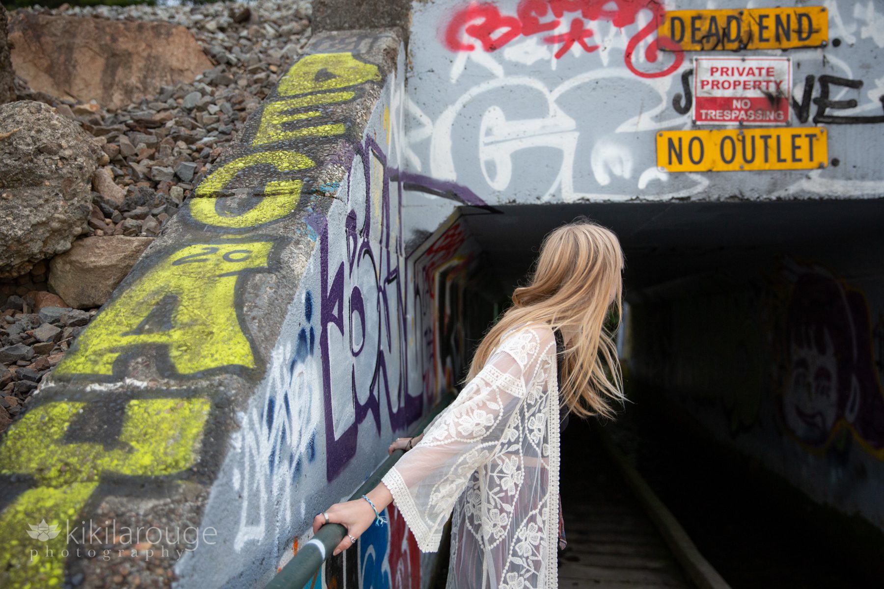 Young blonde girl looking away holding graffiti railing