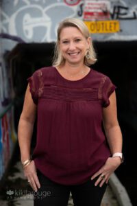 Blonde woman in maroon top by graffiti wall