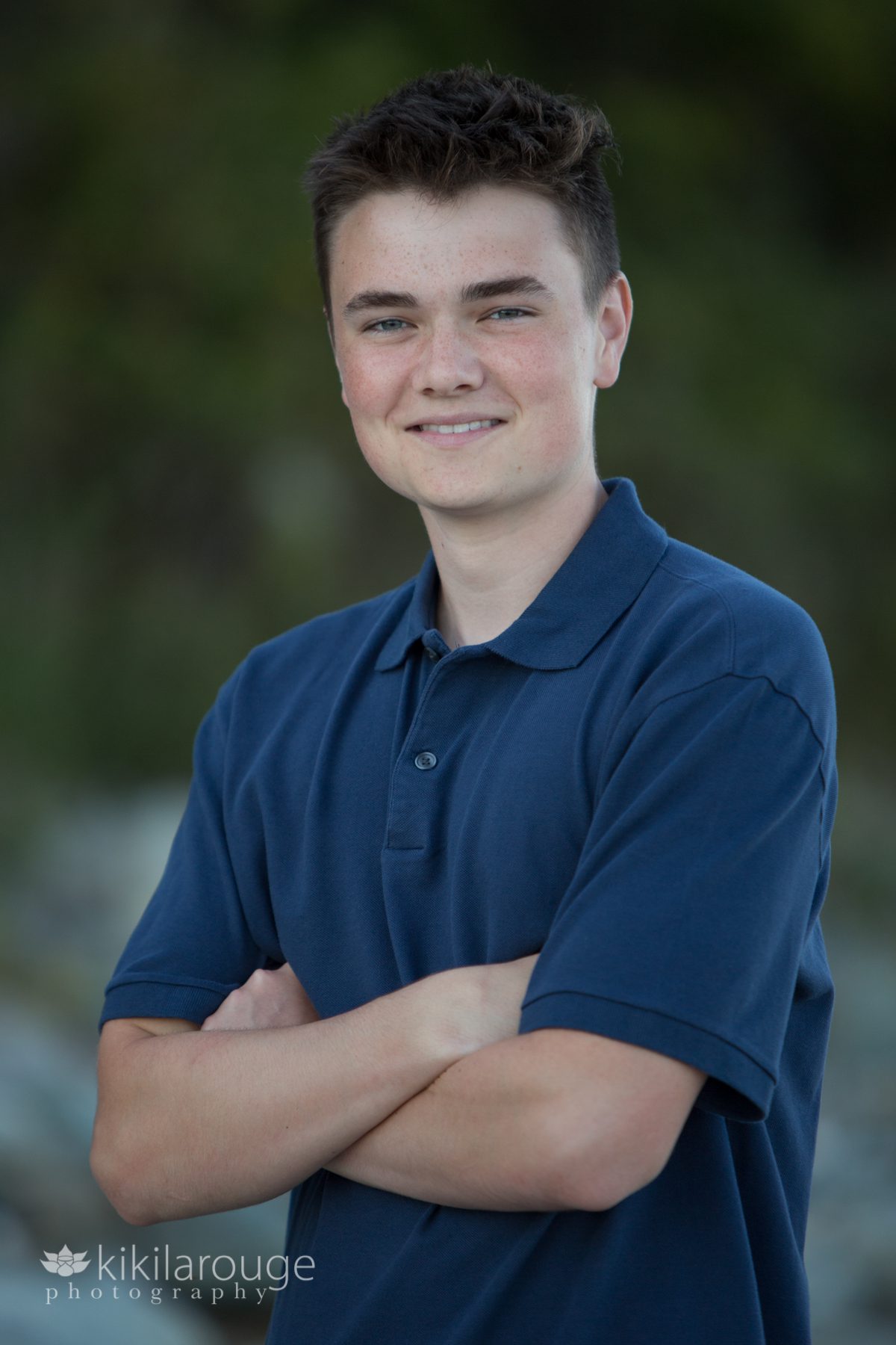 Senior portrait boy folded arms in dark blue shirt