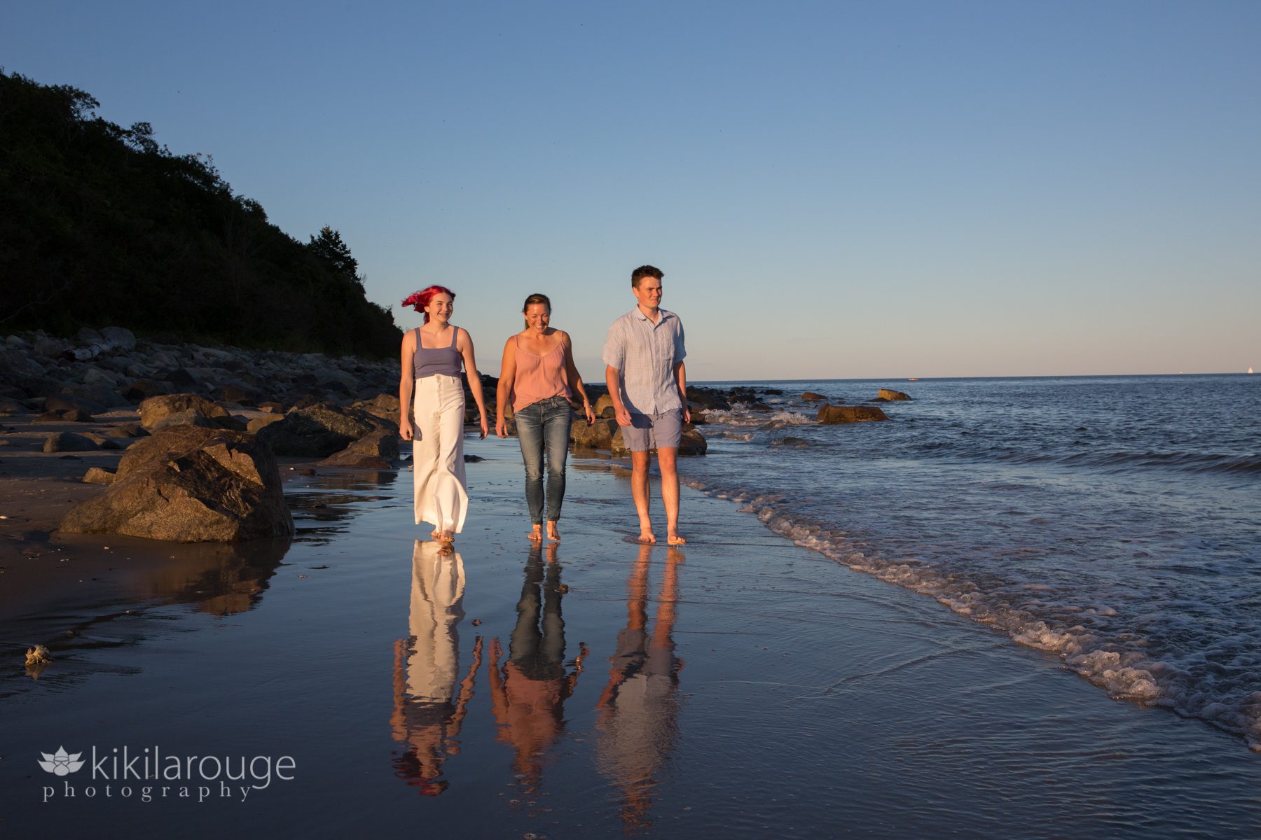 Mom and two kids walking at beach by shoreline with reflection