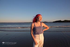 Girl with pink hair smiling at beach at sunset