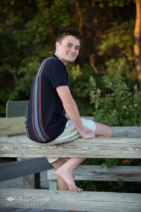 Boy sitting on beach boardwalk looking over shoulder smiling