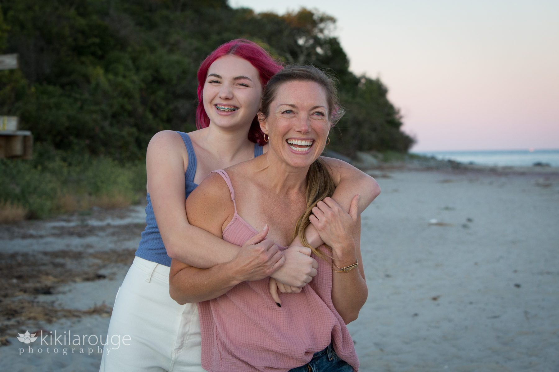 Girl with her mom laughing and hugging at beach