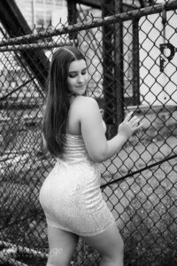 Girl in sparkly nude dres leaning on fence looking down in Boston
