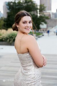 Girl in sparkly dress and hair in bun looking over shoulder