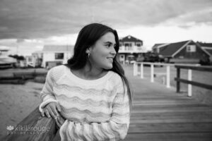 Girl long brown hair leaning on pier looking at sunset