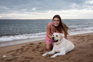 girl in pink dress on beach with yellow lab