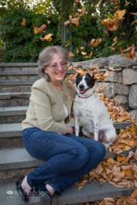 Woman and dog sitting on stone steps with leaves falling on them