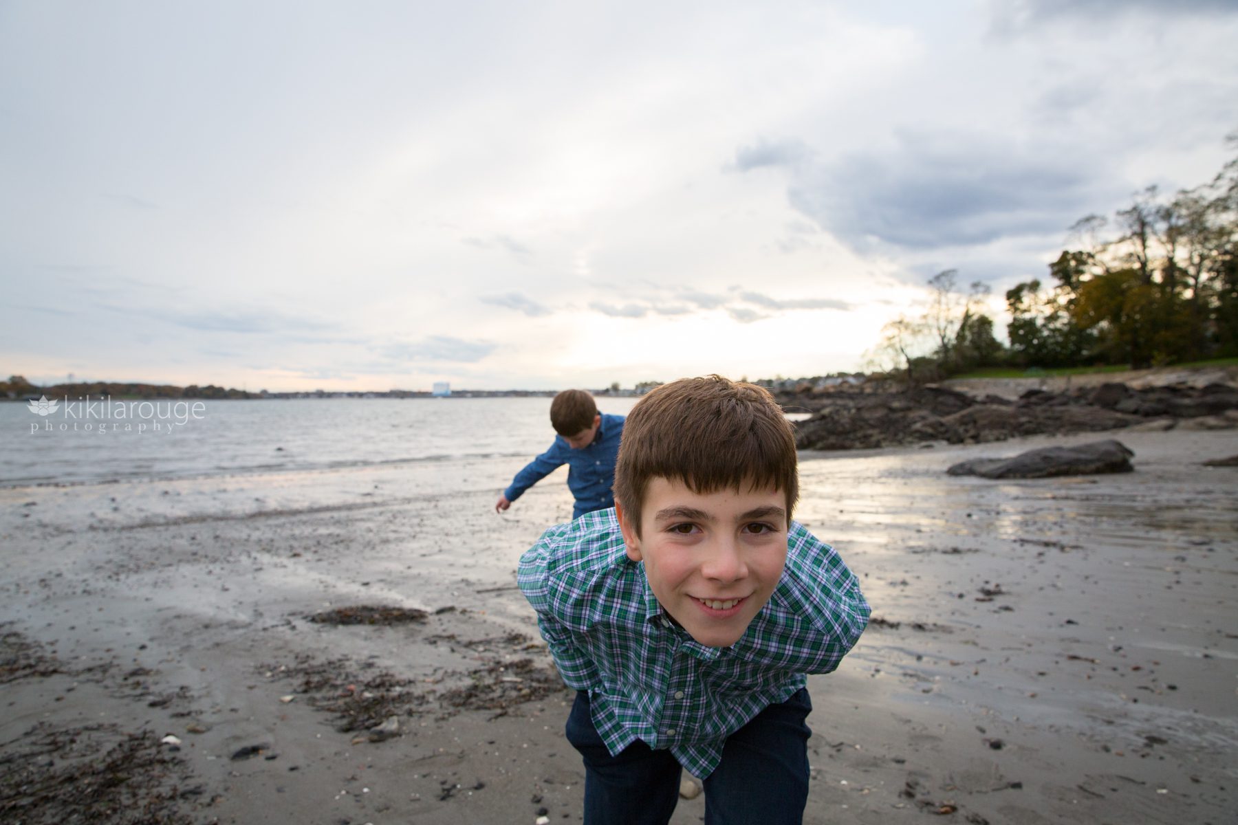 Two boys playing at the beach one looking close into the camera