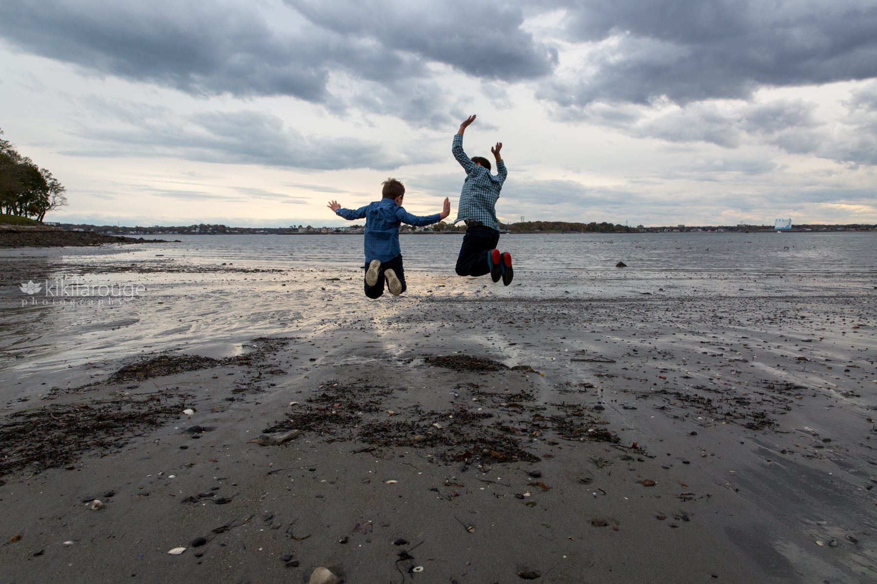 Two young boys jumping at shoreline at beach
