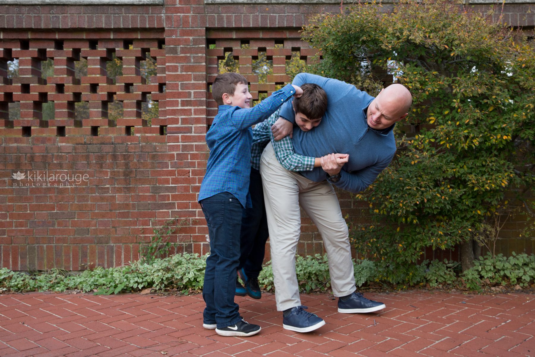 dad playing with two boys by brick wall Lynch Park