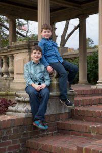 Two boys in jeans sitting on brick stairs in Lynch Park rose garden