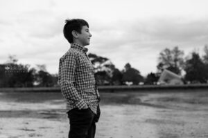 Young boy in plaid shirt at beach looking on horizon