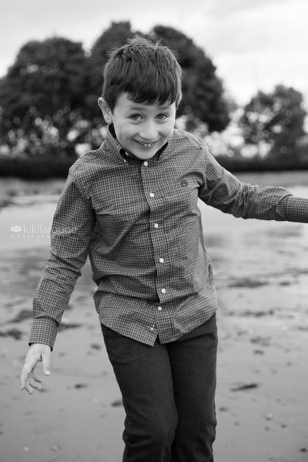 Little boy smiling and playing at the beach in Fall