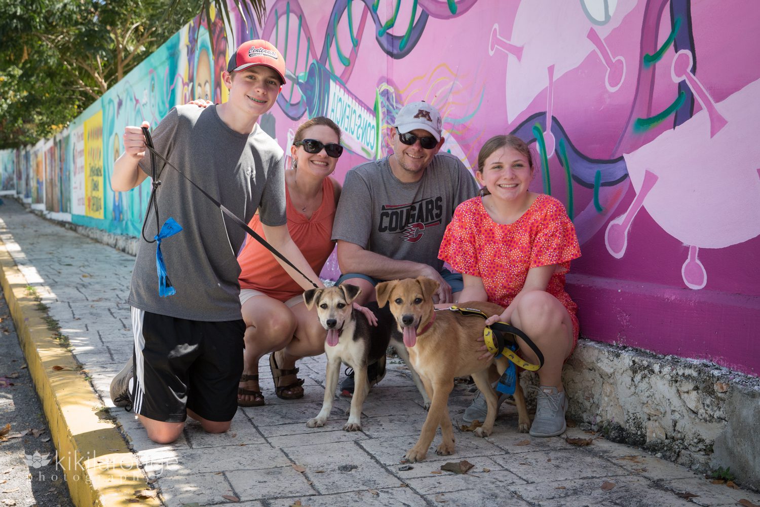 Family of four on side street with street art and two rescue puppies