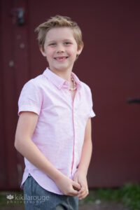 Young boy with front teeth missing smiling in pink button down shirt