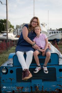 Woman and son sitting on a blue tractor in the NBPT boat yard