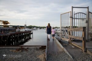 Mom and son walking together down small pier towards Merrimac River