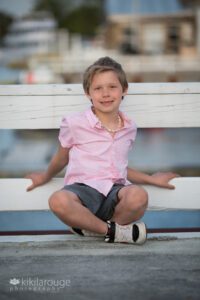 Cute blonde boy sitting on boat pier with a pink shirt in Newburyport MA