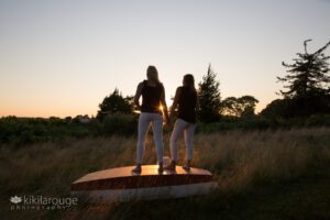 Couple holding hands at sunset in silhouette on turned over small boat
