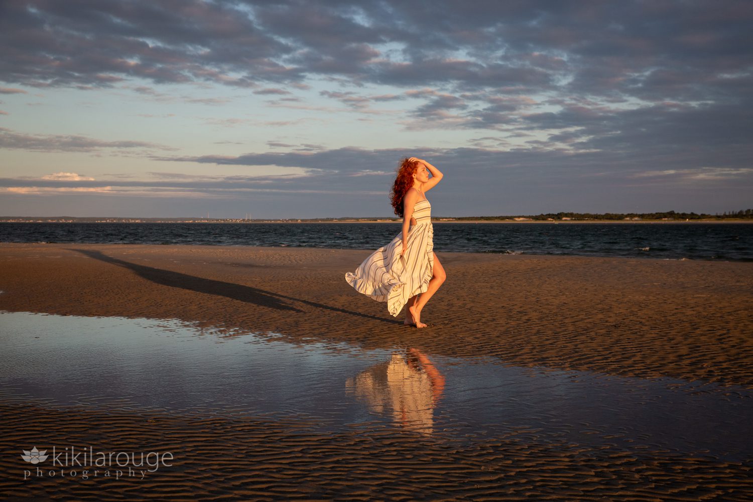 Sunset with dramatic skies at beach with girl in dress and reflection in tide pool at beach