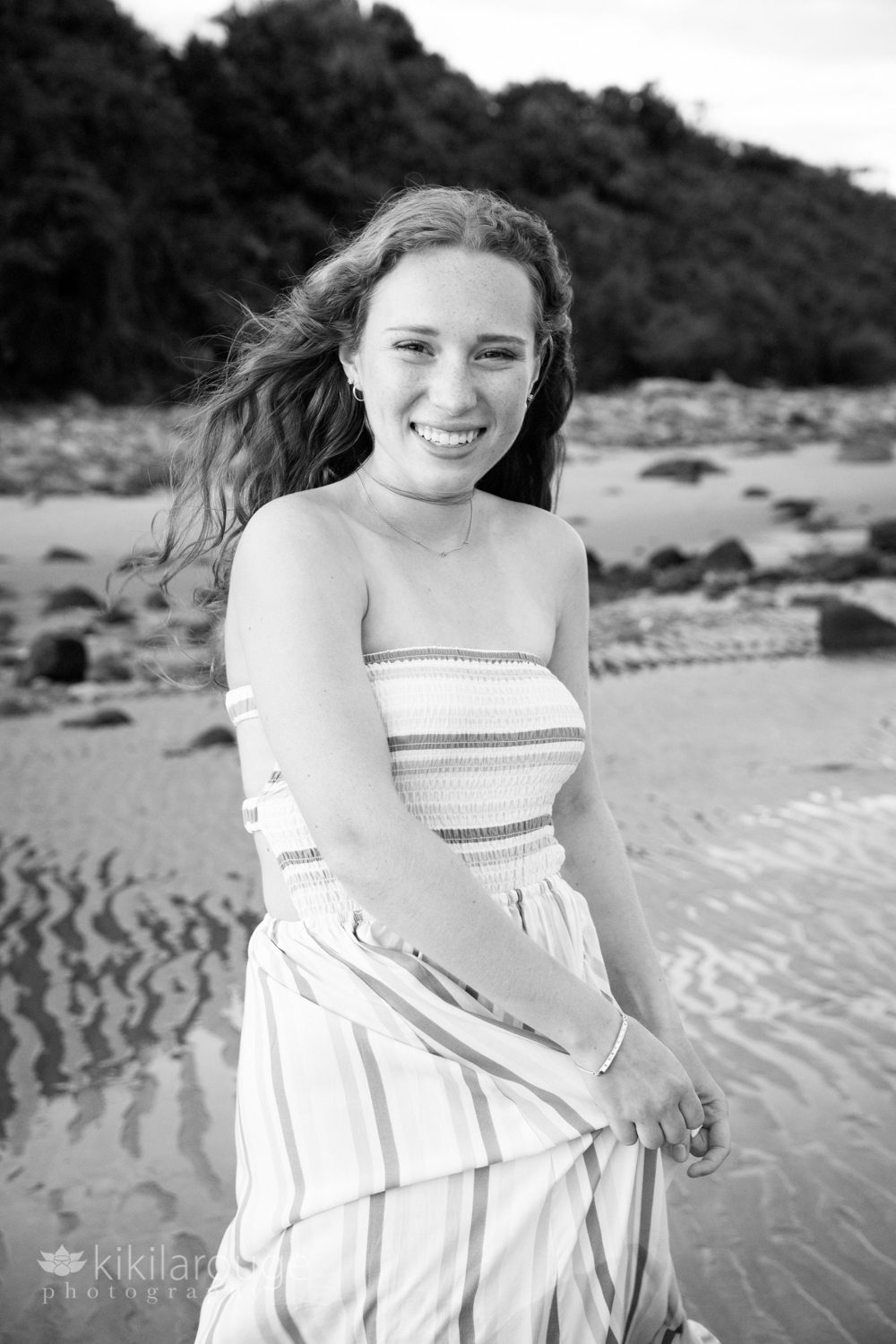 BW teen girl laughing while dancing in dress on beach