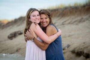 Teen girl in lilac dress hugging Mom in blue tank