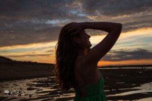 Silhouette of teen girl with long wavy hair at dramatic Plum Island sunset