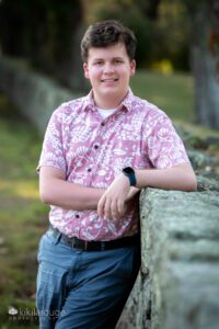 Teen Senior Boy in Pink Hawaiian shirt leaning on stone wall