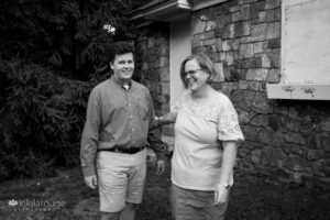 BW mom and senior boy at shoot laughing by stone wall