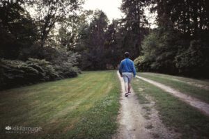 Senior boy walling down path into the forest