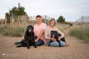 Teen boy with Mom and their two black dogs sitting on beach dune trail