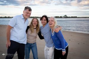 Family portrait of four with two teens everyone laughing at beach