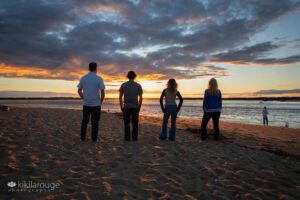 Family of four facing sunset with dramatic clouds at Plum Island