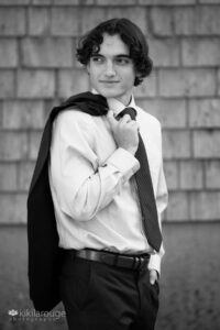 Teen boy with suit jacket over shoulder in shirt and tie looking left