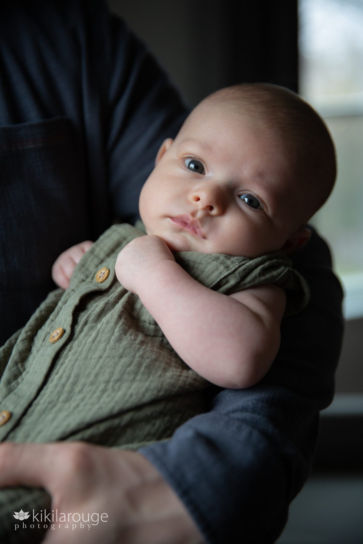 Two month old baby looking at the camera in dad's arms