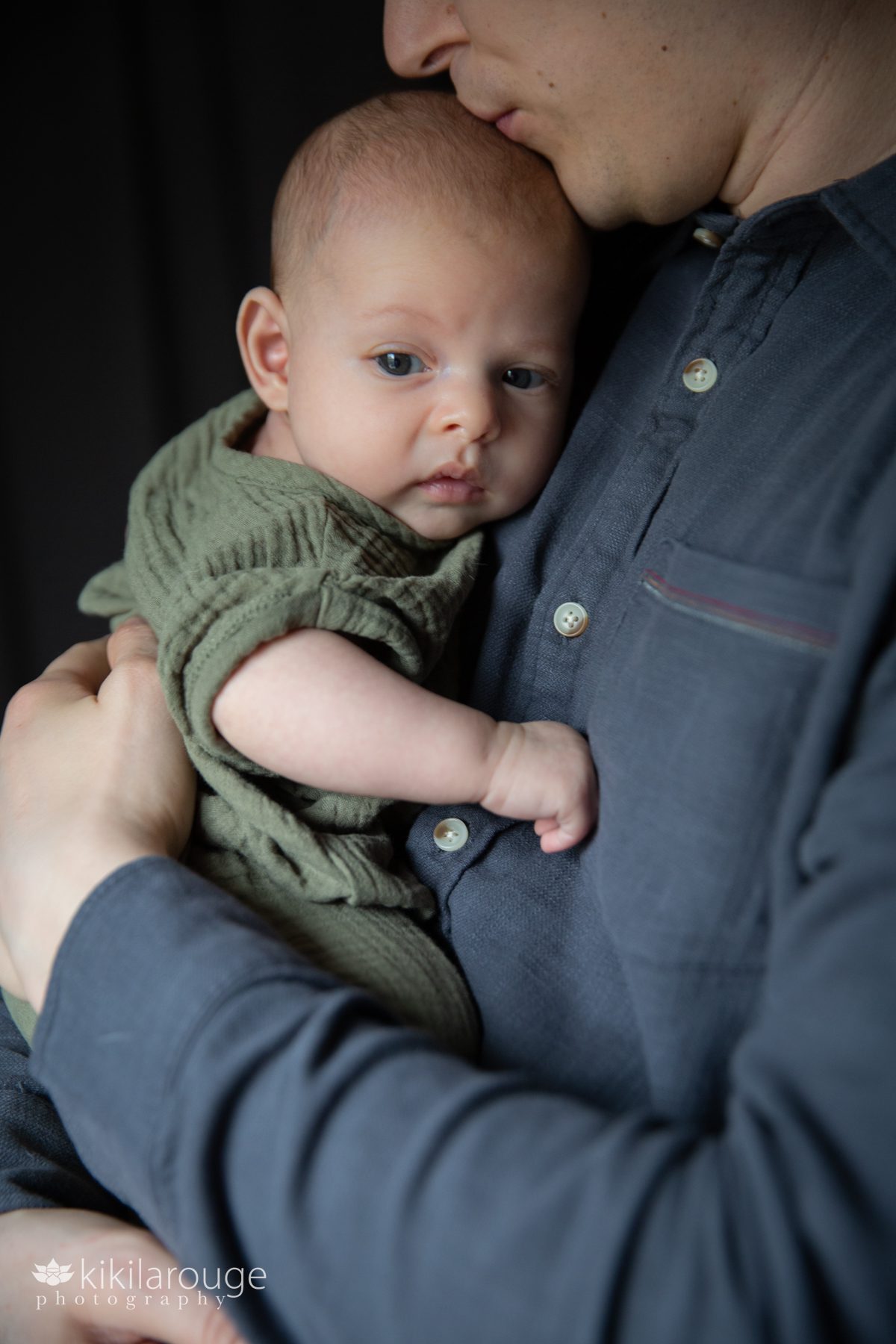 Dad holding two month old baby in green onesie