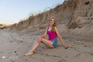 Senior portrait blonde girl on beach dunes in shorts and pink top