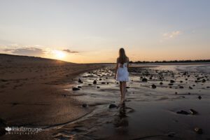 Girl in white dress walking off into the sunset at Plum Island beach