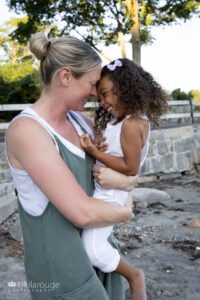 Mom in green jumper giggling and snuggling with 4.5 year old daughter in white jumper