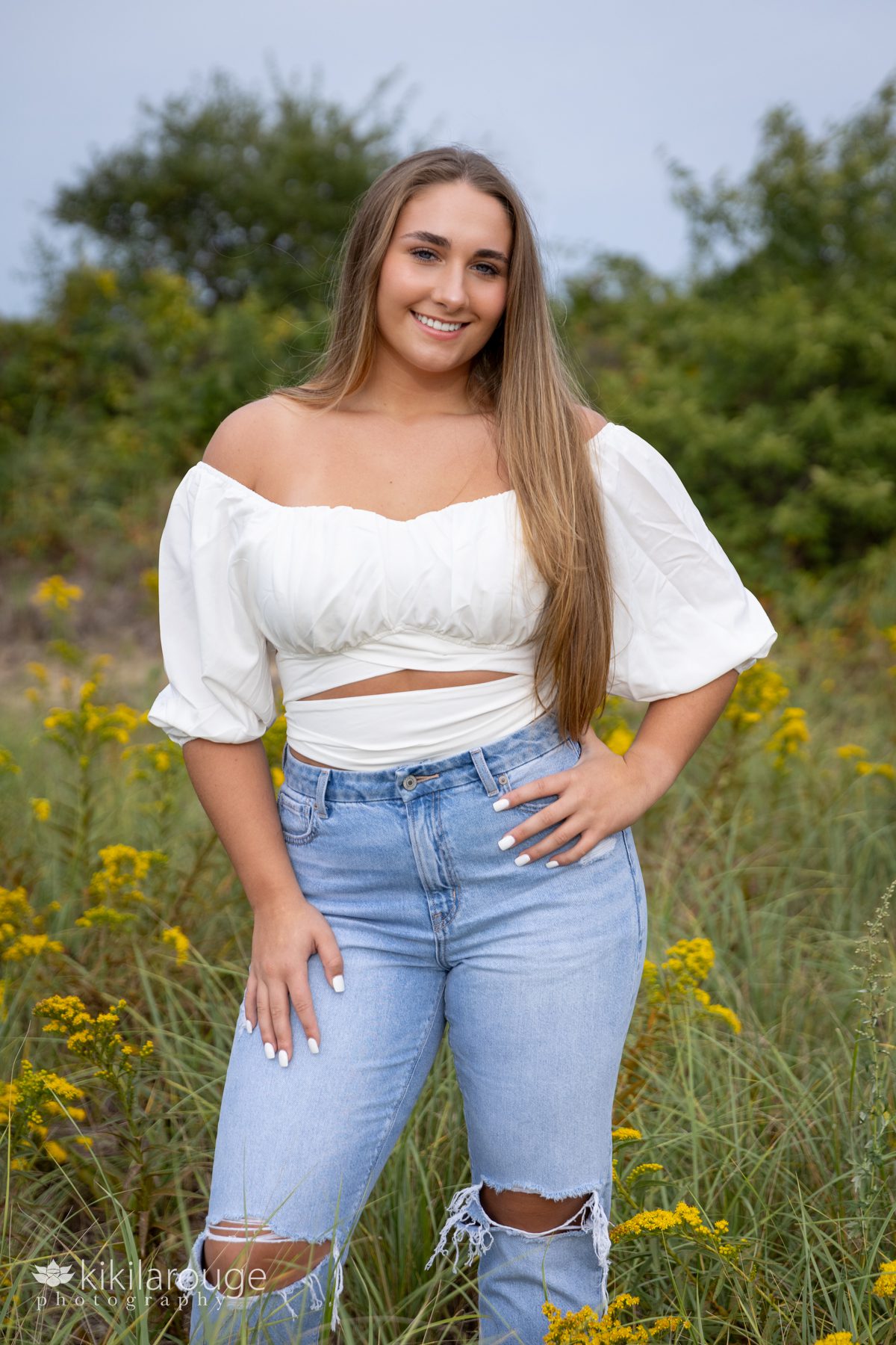 Triton Senior Portrait Girl in Jeans with white top tied in back at beach in goldenrods