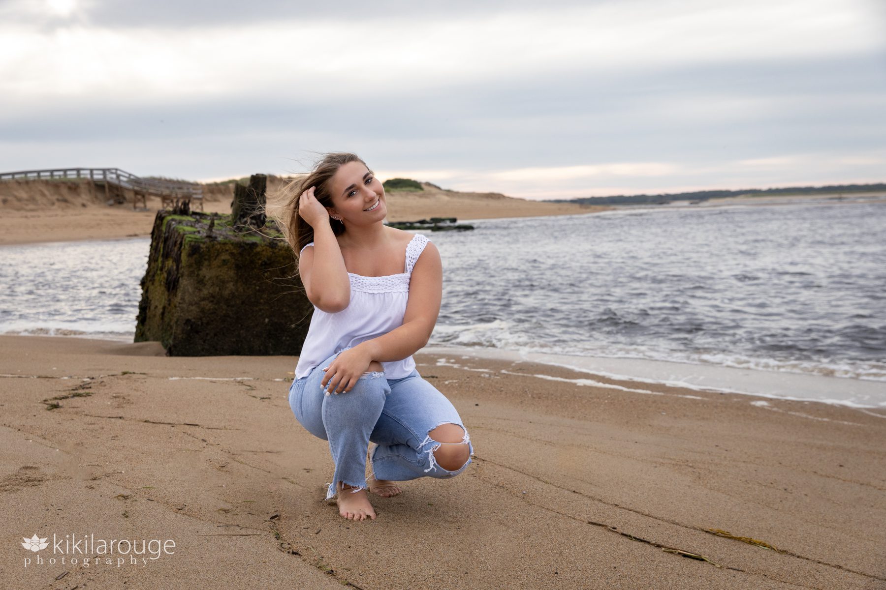 Triton Senior Portrait Girl in Jeans with white top tied in back at beach water's edge